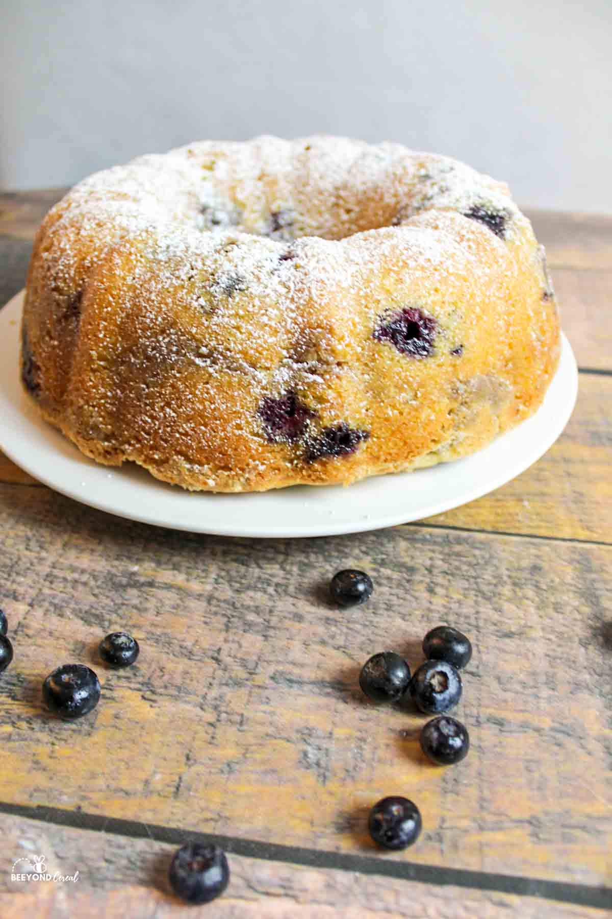 A full bundt cake with scattered blueberries in front