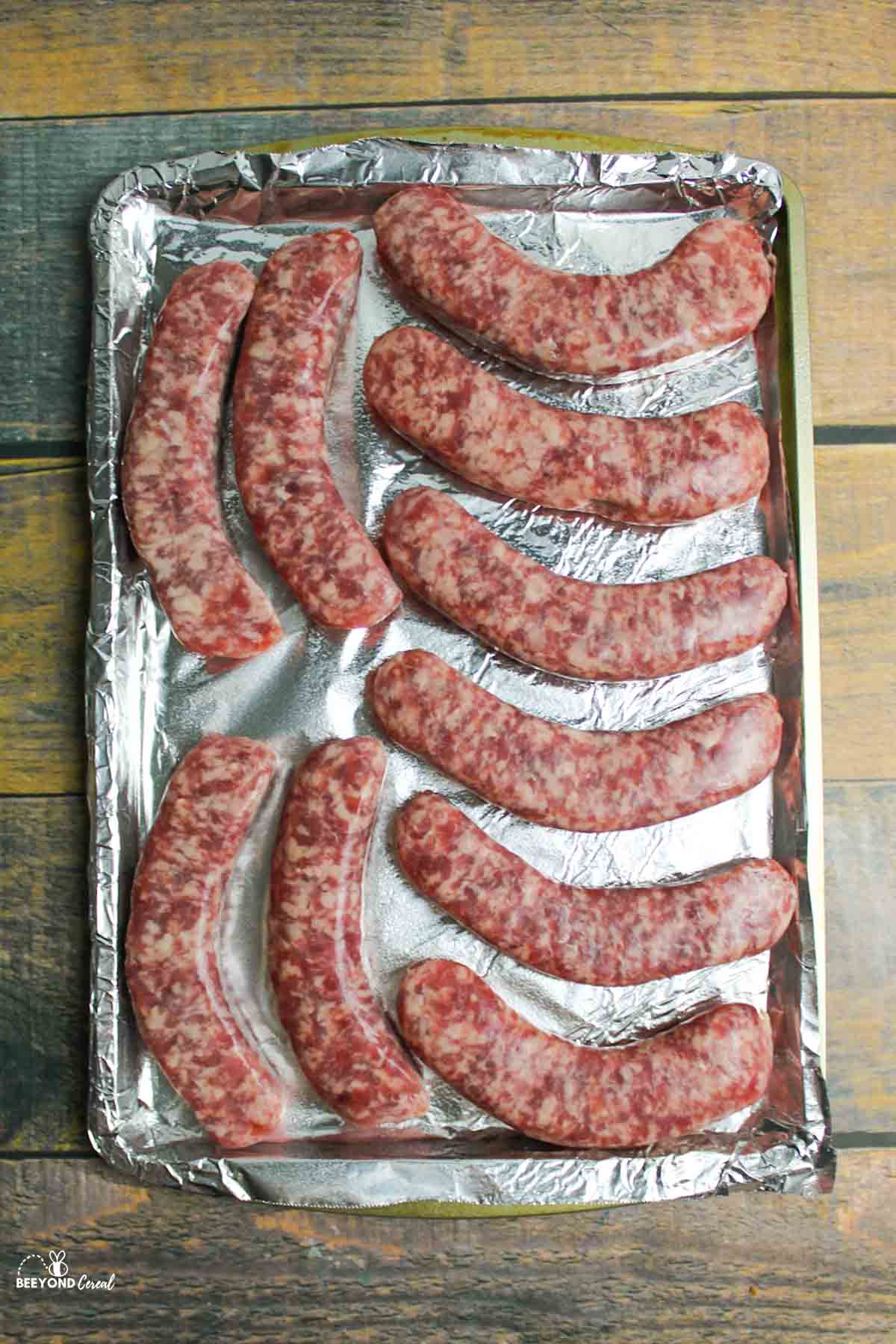 uncooked brats layed on a baking sheet ready to be cooked