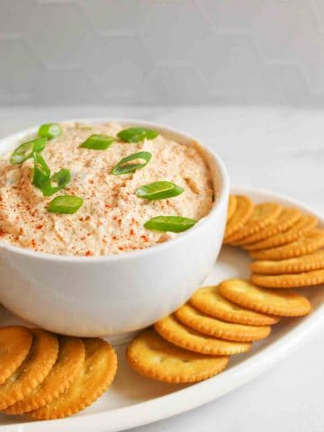 a bowl of trout dip on a white platter filled with Ritz crackers