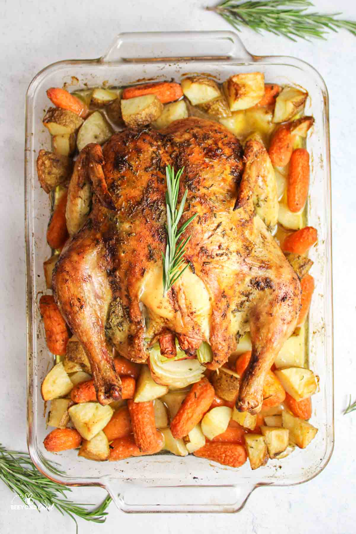 a baking dish with baked chicken, potatoes and carrots.