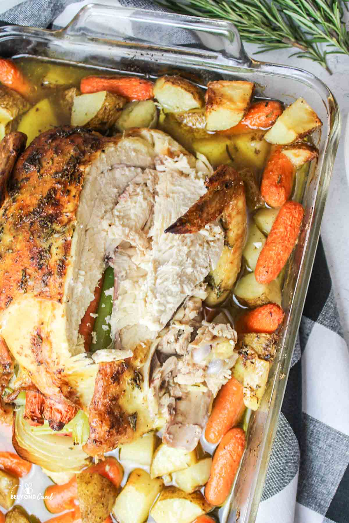 sliced chicken in a baking dish with carrots and potatoes