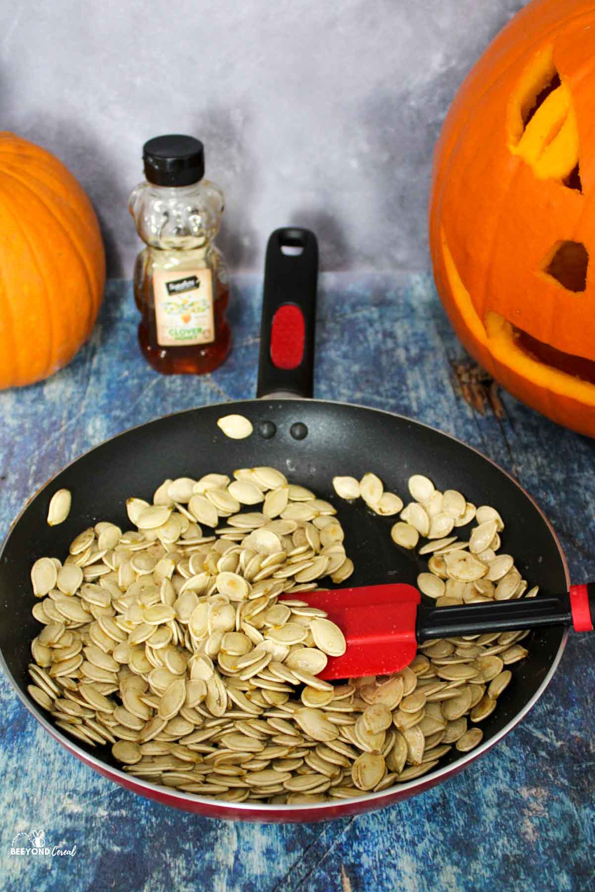 a skillet filled with honey and cinnamon tossed pumpkin seeds