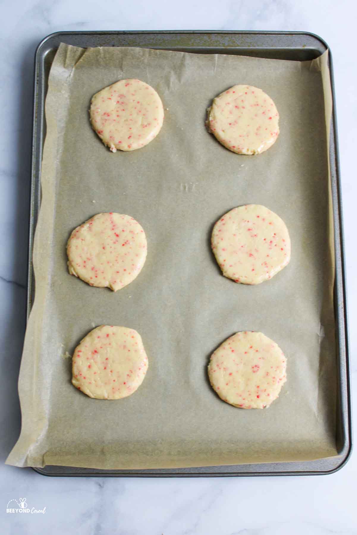 flattened cherry chip cookie on a parchment lined baking sheet.