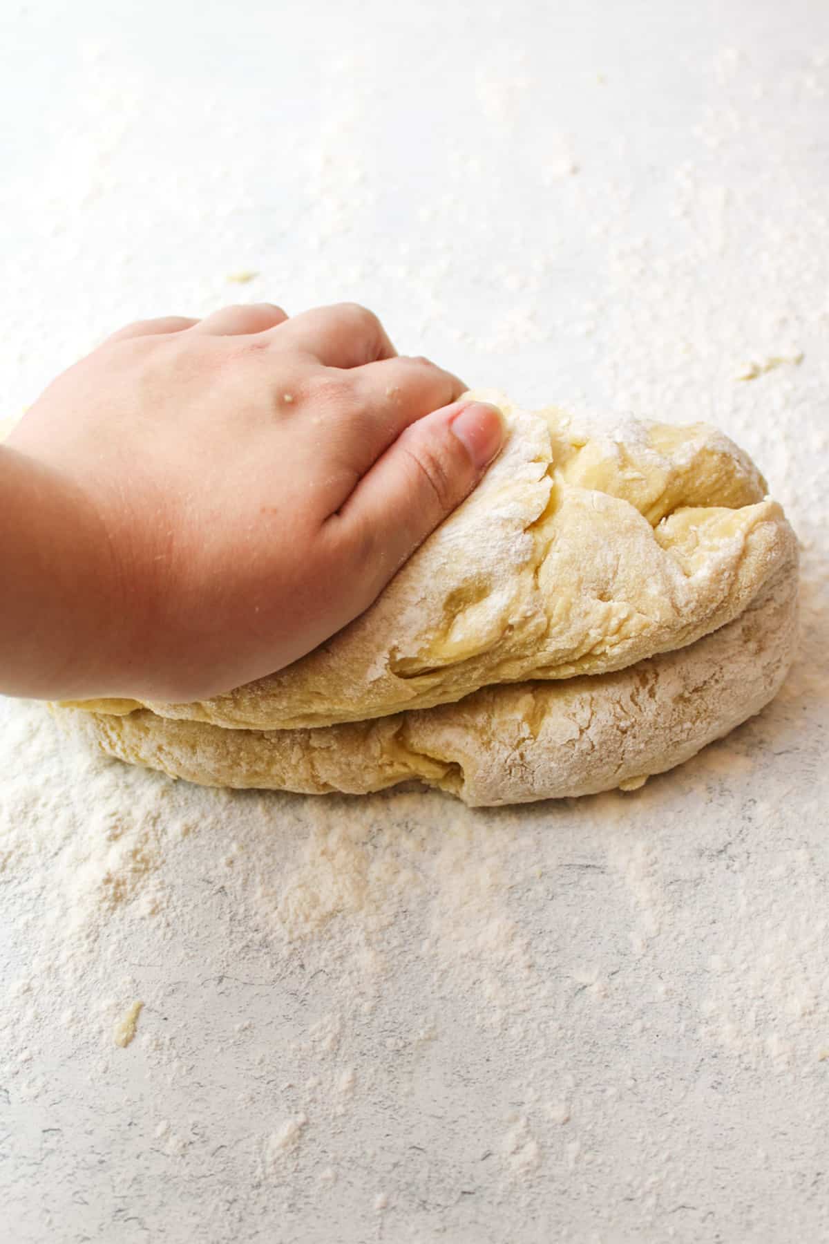 using a hand to spread he cinnamon over the dough