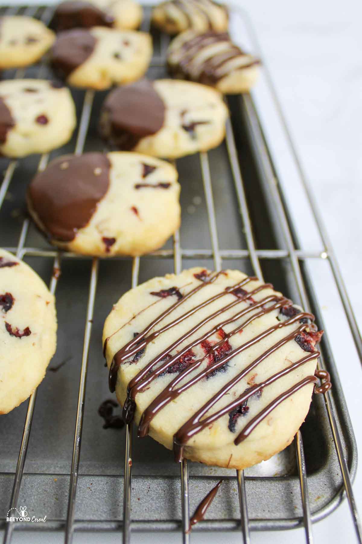 chocolate dipped and drizzled shortbread cookies on wire rack over cookiesheet