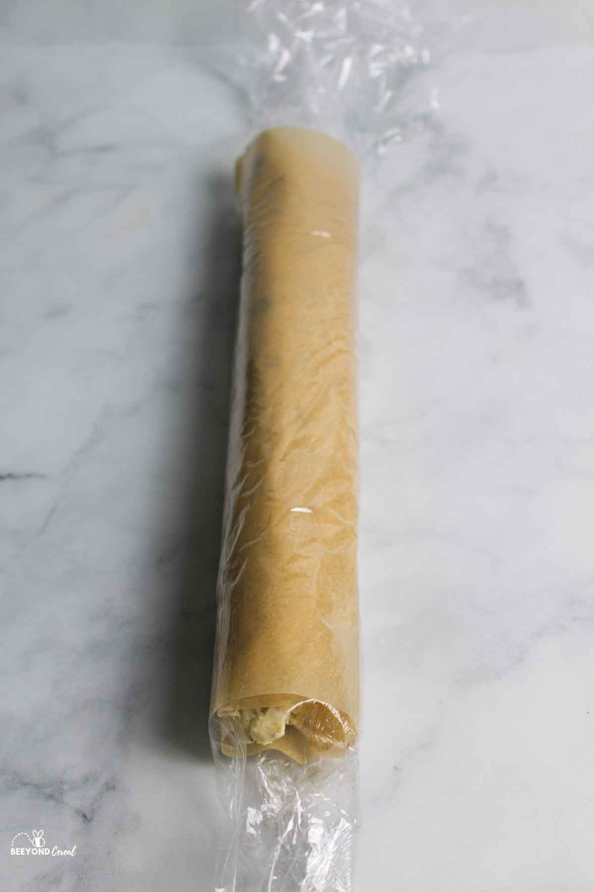 parchment papaer and plastic wrap rolled cookie dough.