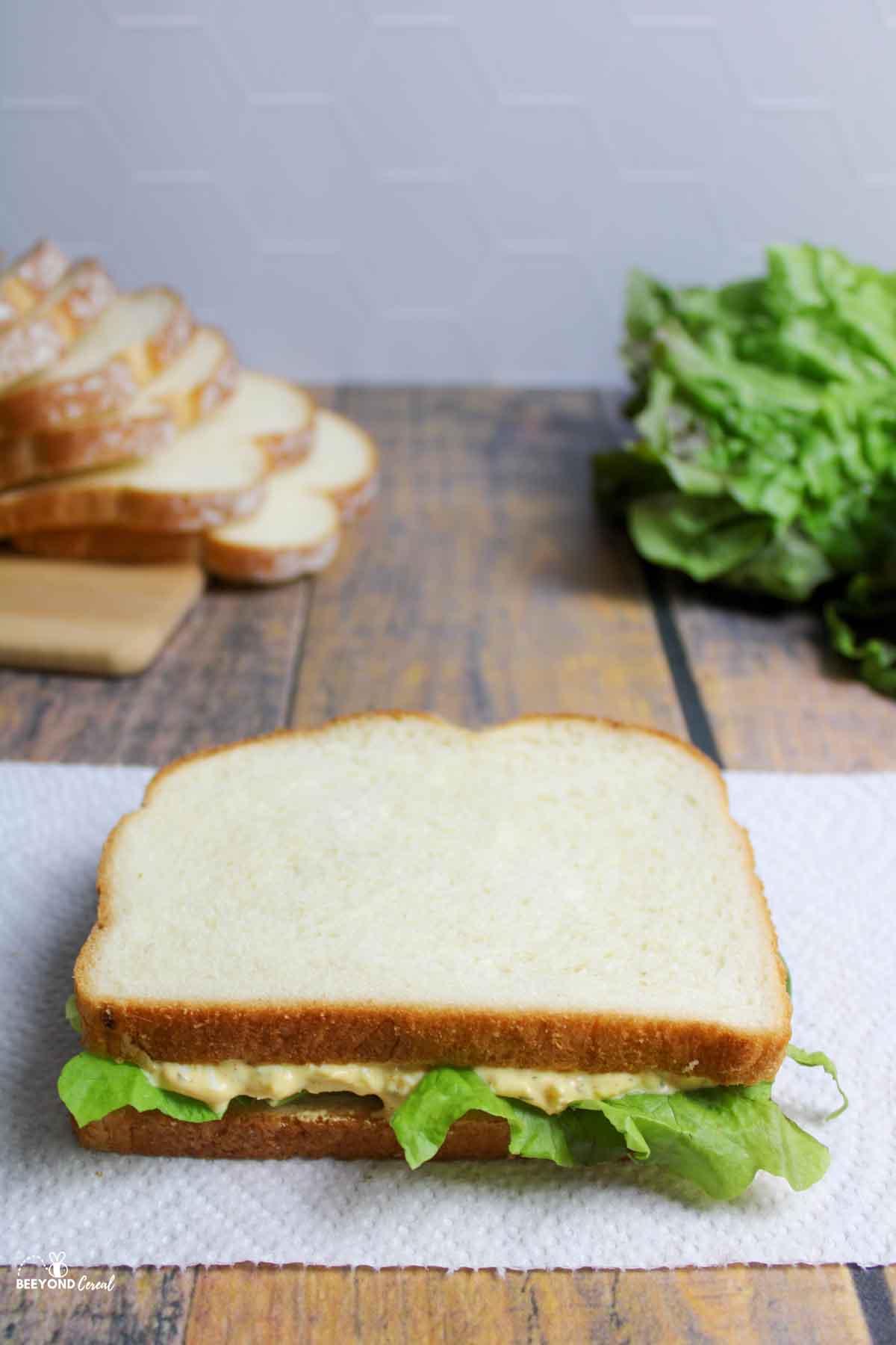 egg salad sandwich with lettuce on paper towel.