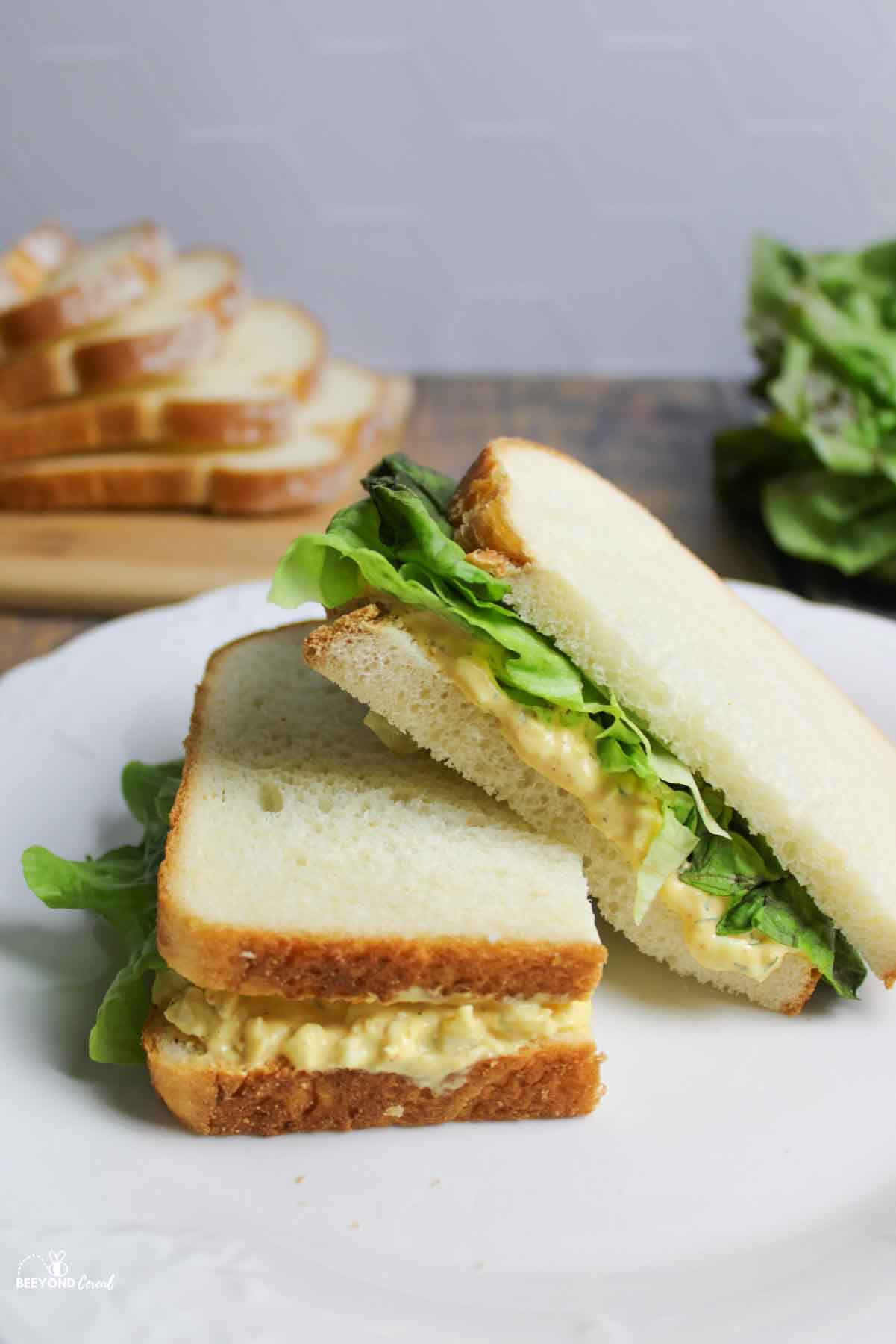 a half of an egg salad sandwich resting off of the other.