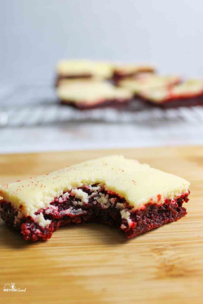 red velvet cheesecake brownie on cutting board missing a bite