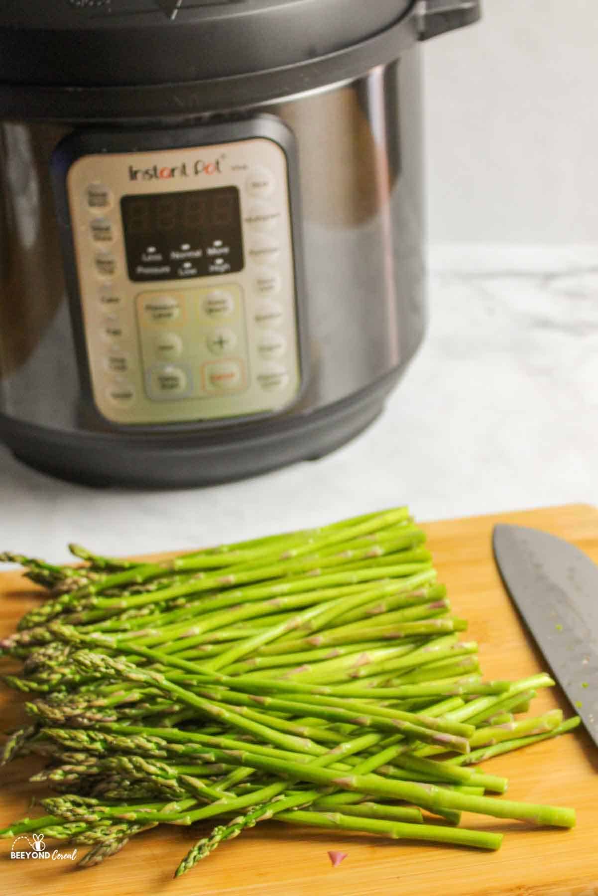 sliced asparagus on wooden board in front of instant pot