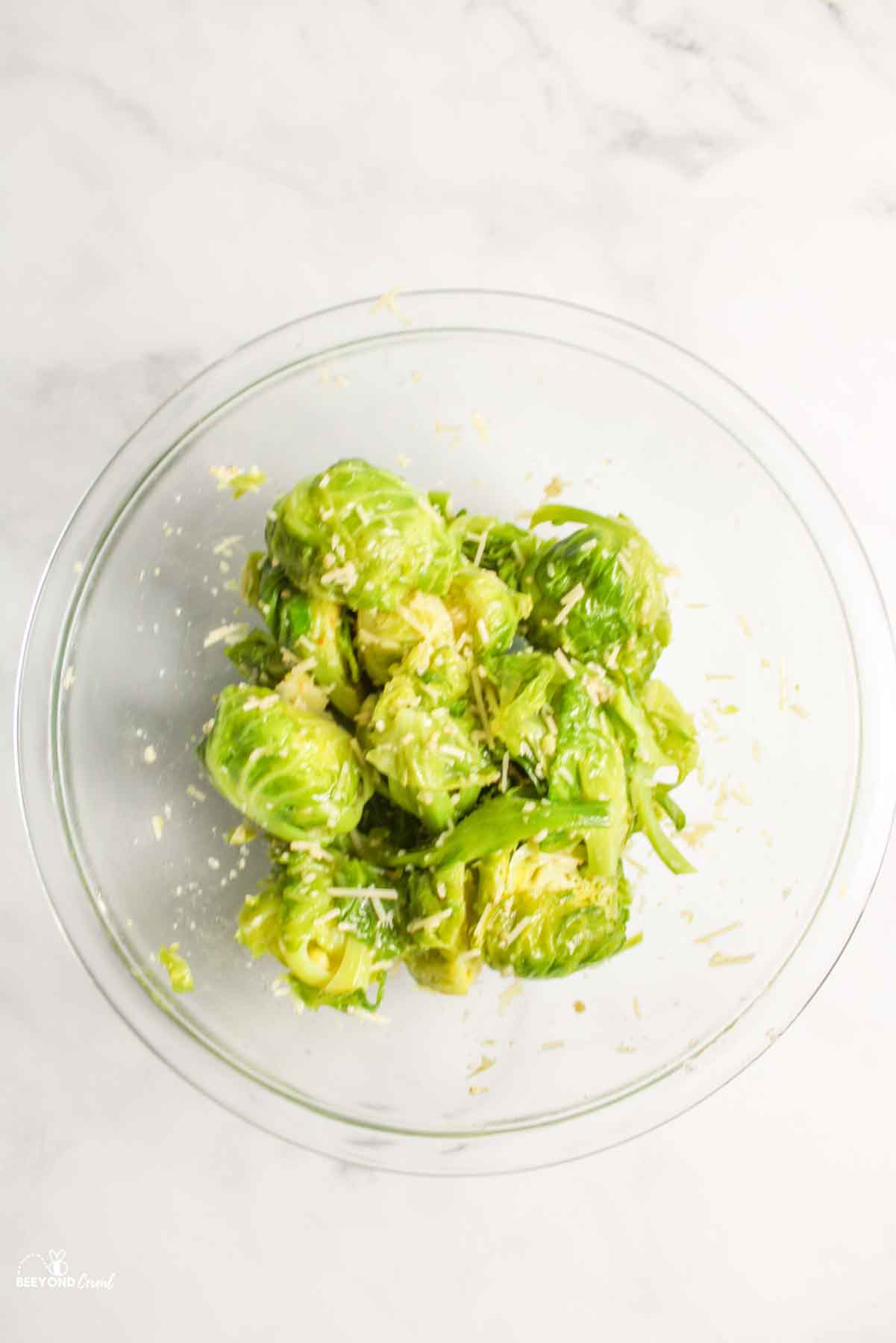 aerial view of brussel sprouts in glass bowl with seasonings and cheese