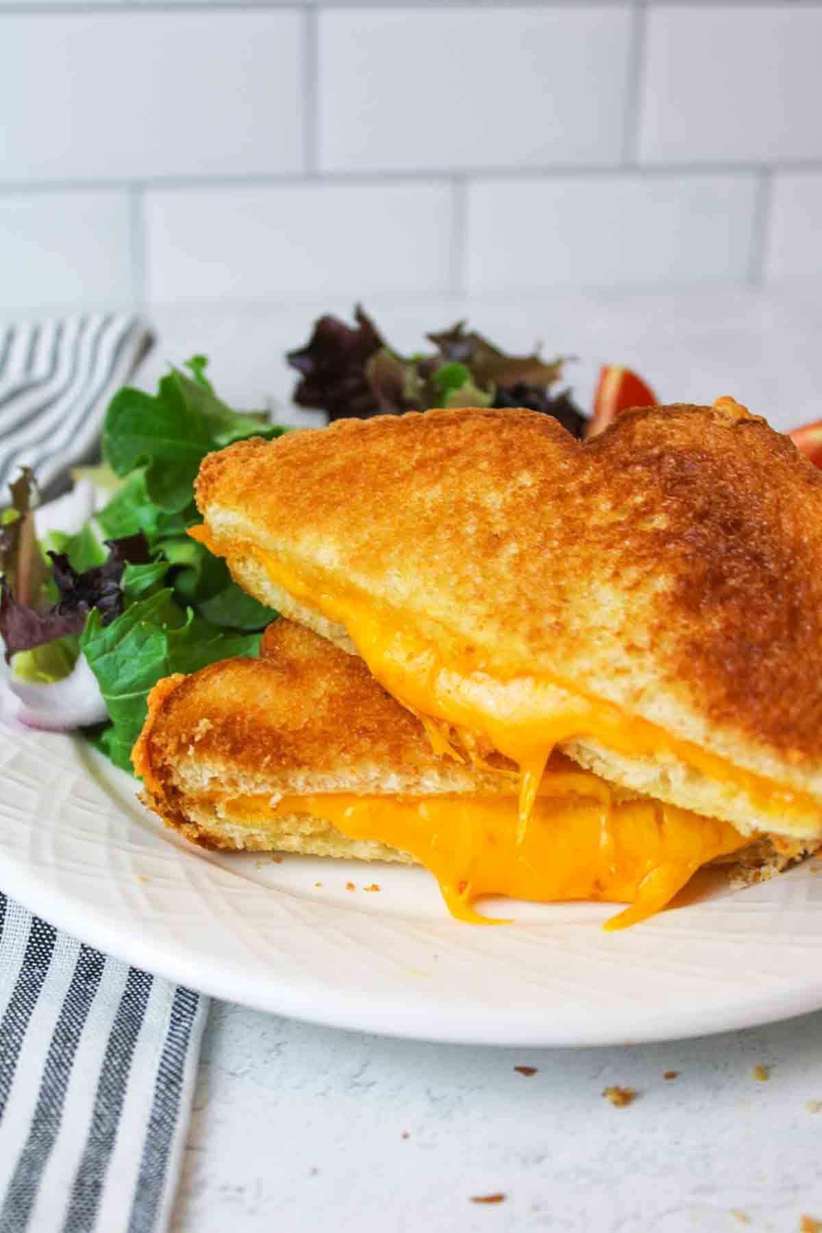 two stacked microwave grilled cheese sandwich halves on a plate.