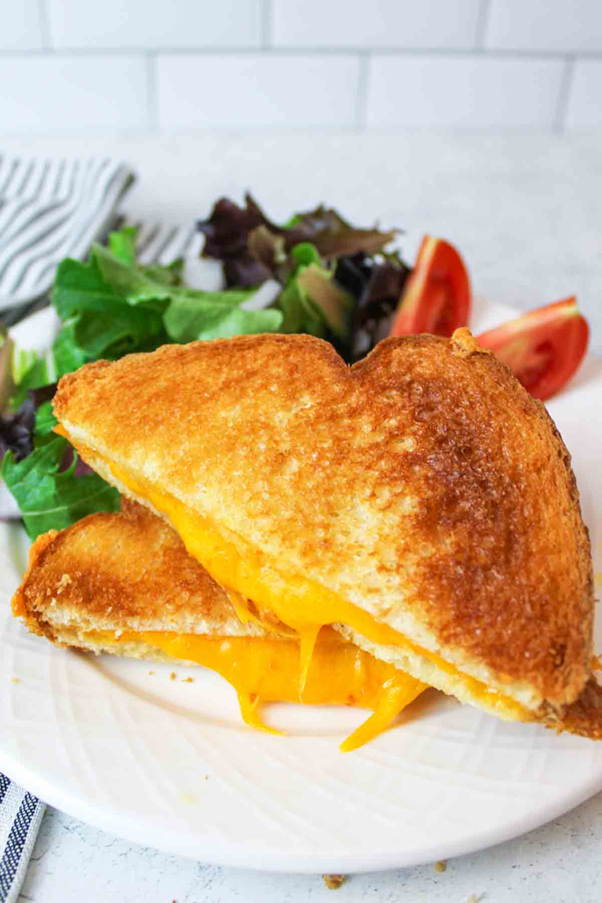 microwave grilled cheese sliced in half and on a plate with a salad.