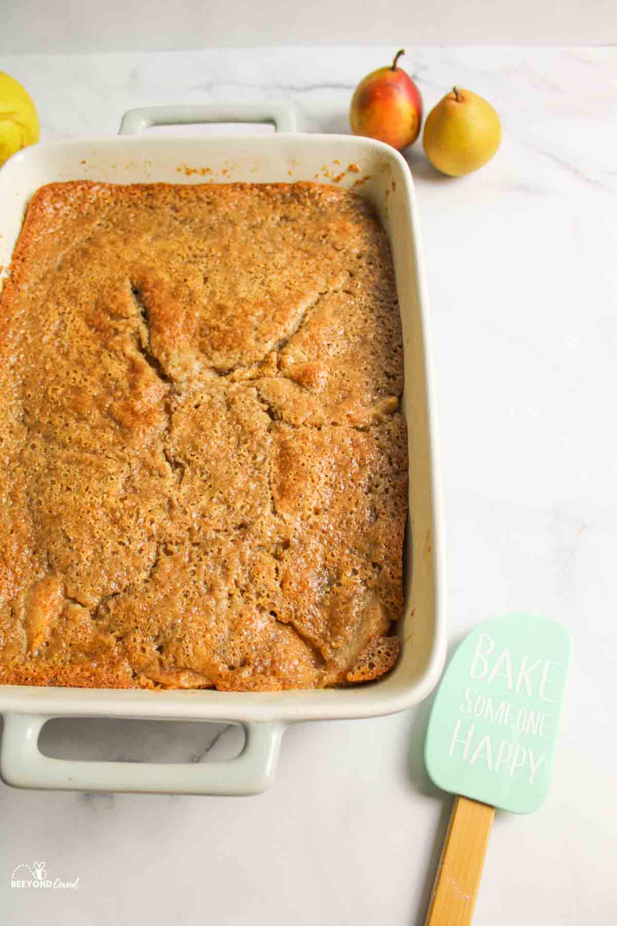 baked pear cobbler with fresh pears and spatula to the sides
