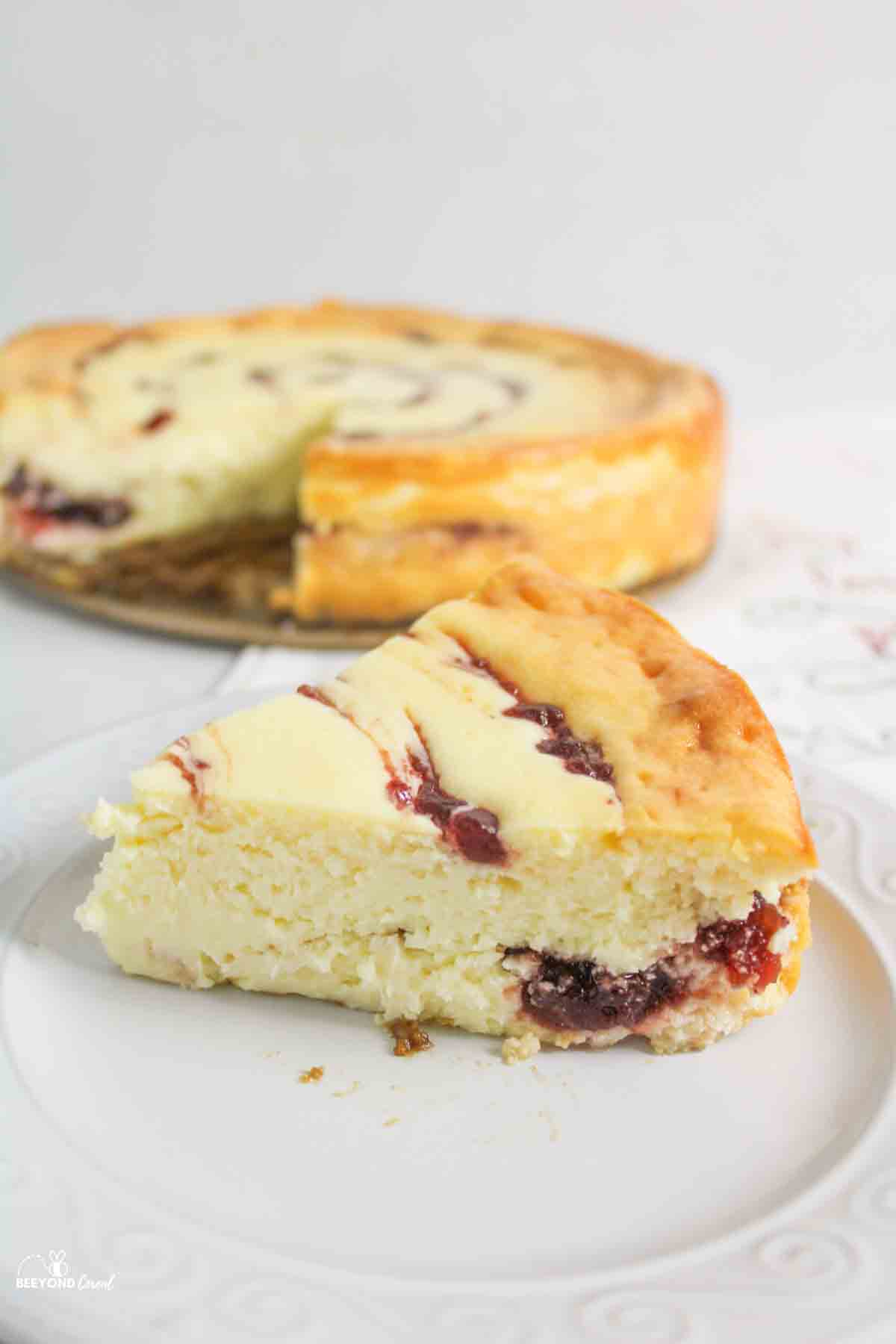 a slice of cranberry white chocolate cheesecake in front of the remaining cheesecake.