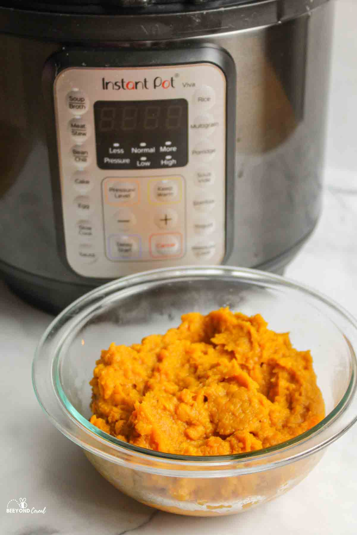 a glass bowl filled with mashed sweet potatoes in front of an instant pot