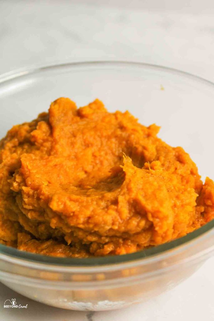an upclose view of mashed sweet potatoes in a glass bowl