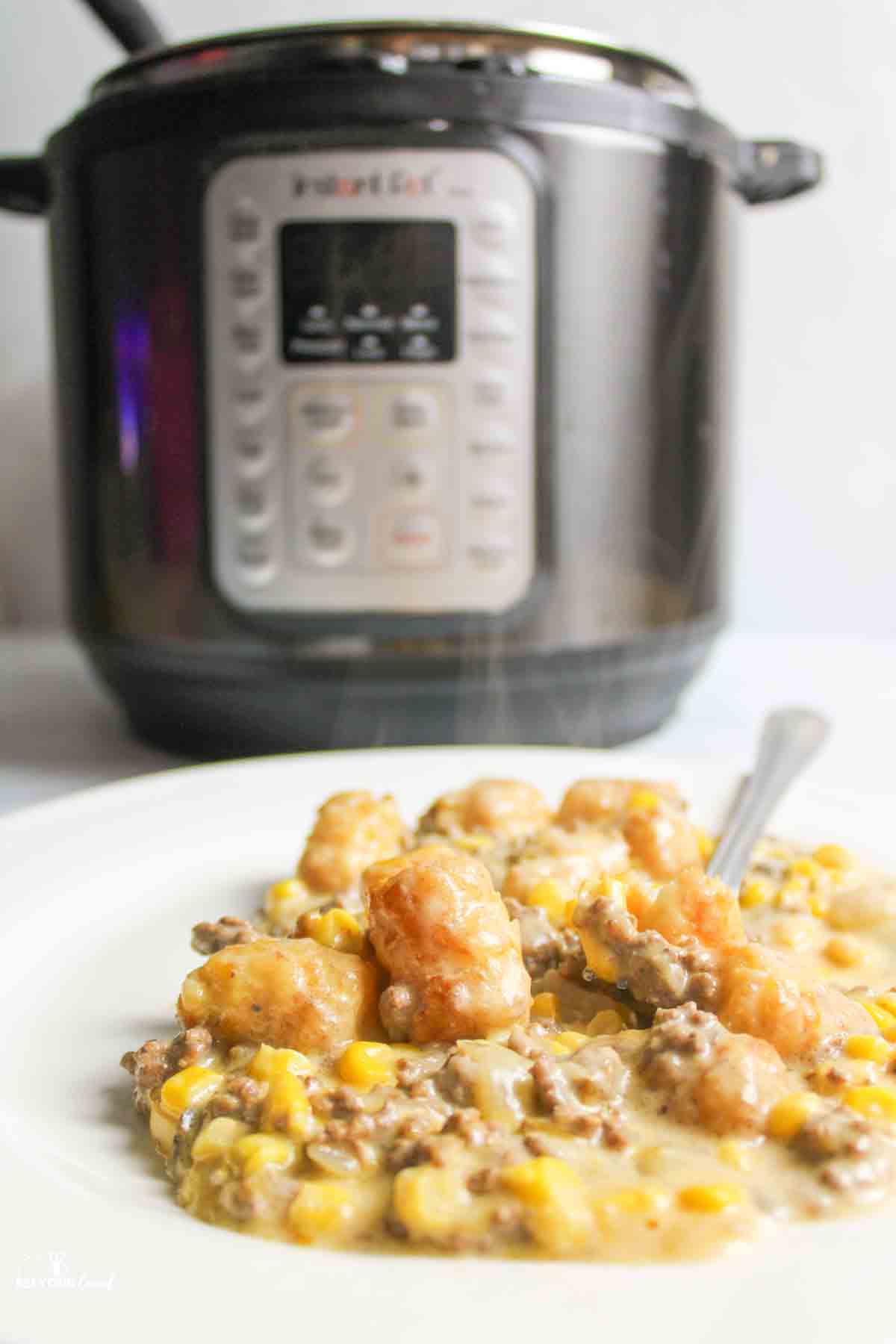 a plate with steamy tater tot casserole in front of the instant pot.