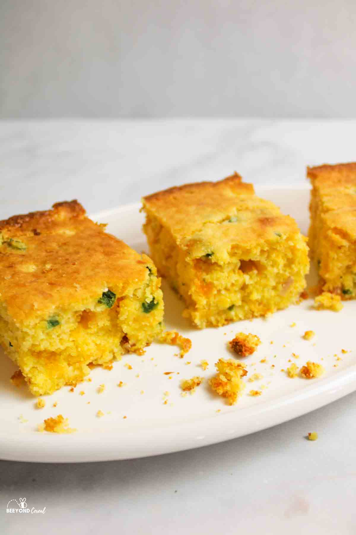 three squares of jalapeno cornbread on an oval plate