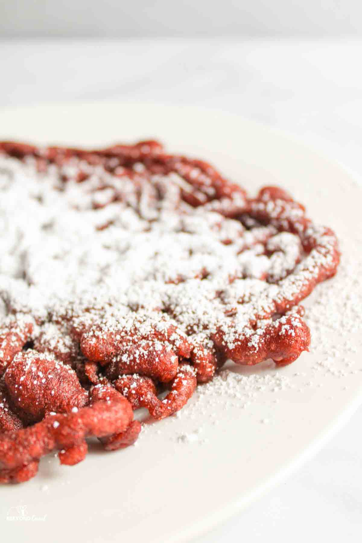 red velvet funnel cake with powdered sugar on top.