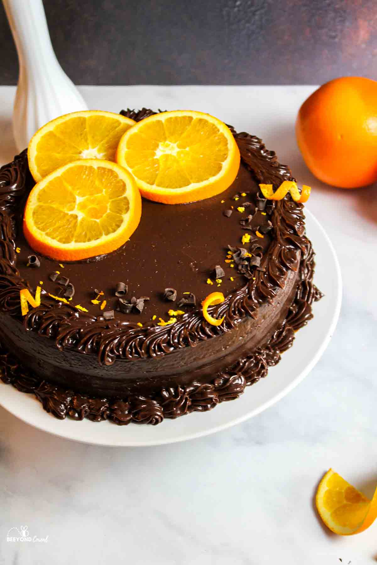 an orange slice and zest garnished chocolate orange cake.