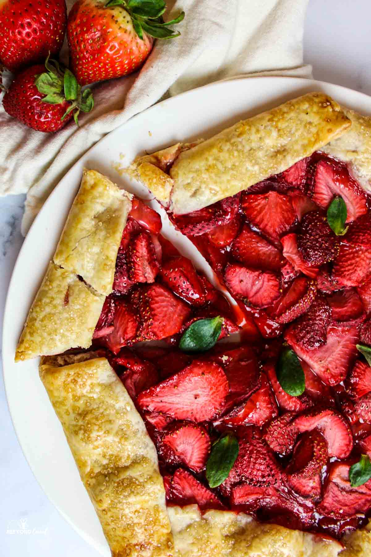 aerial view of a sliced strawberry galette next to fresh strawberries