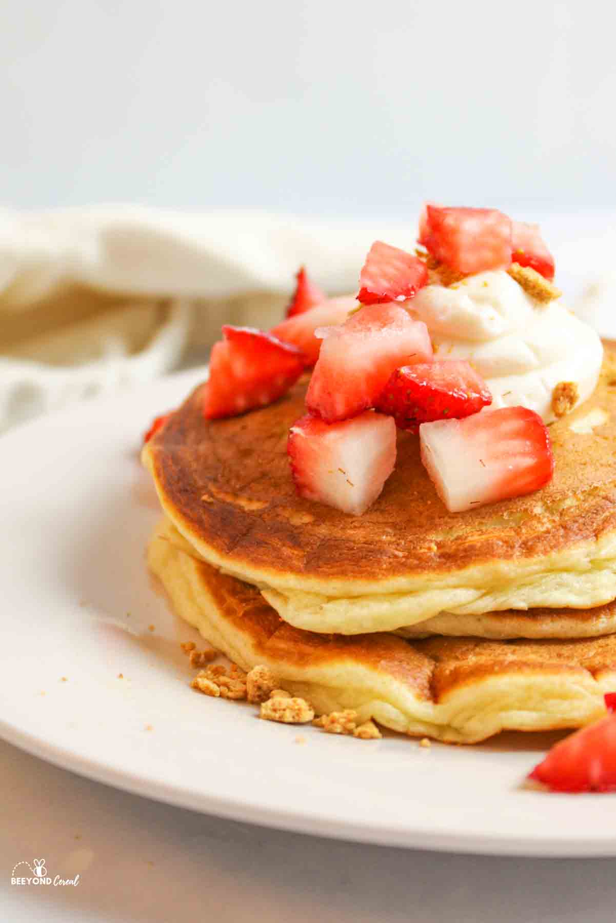 a stack of panckaes topped with cream cheese and fresh diced strawberries