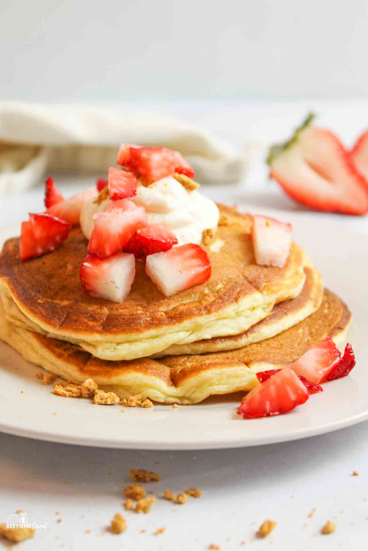 side view of a plate stacked with strawberry cheesecake pancakes