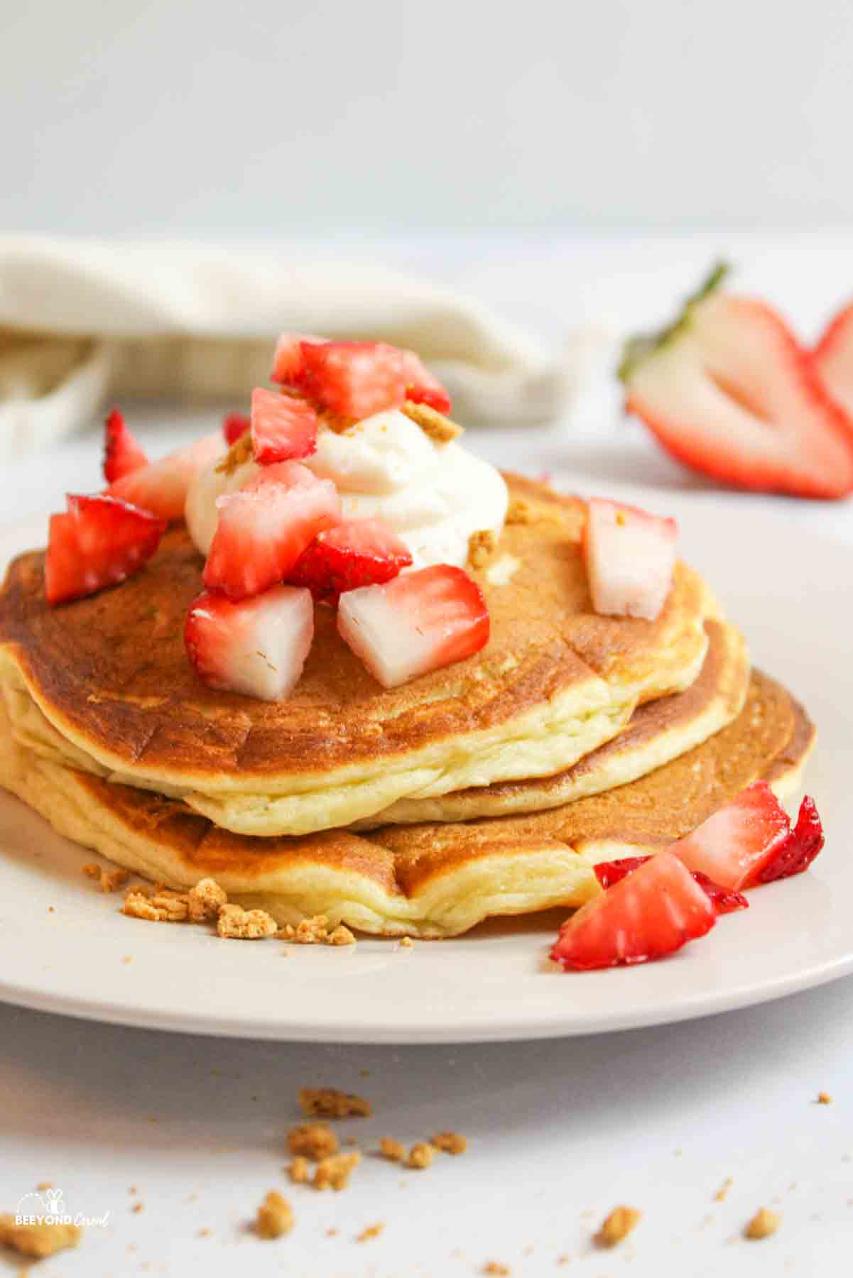 a plate stacked with strawberry cheesecake pancakes.