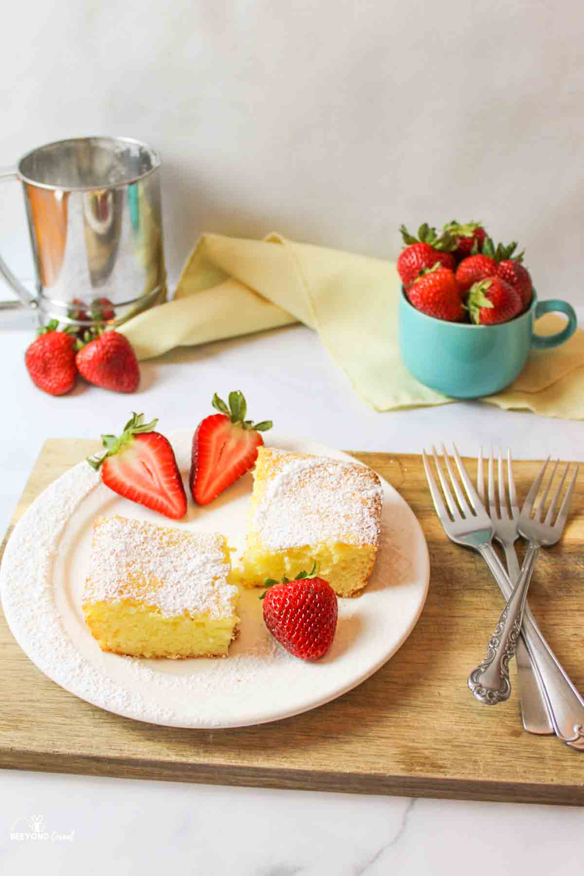 two sliced lemon squares on a plate with fresh strawberries.