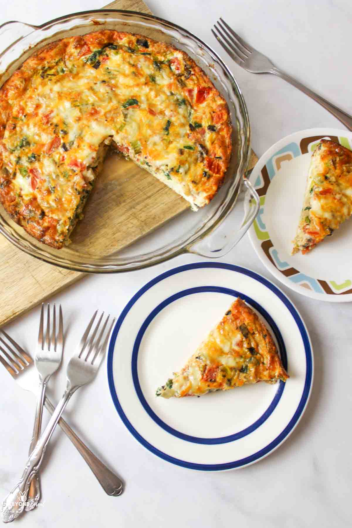 aerial view of sliced veggie quiche on plates and in a glass pie plate next to forks