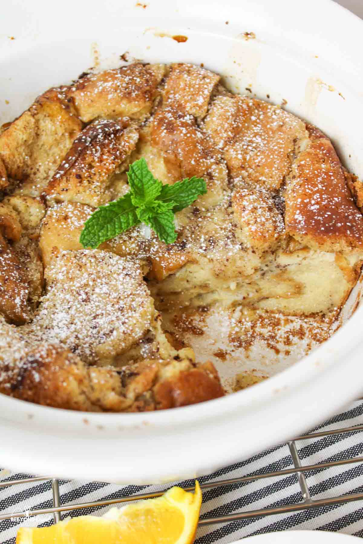 a close up of a sliced bread pudding in a white round casserole dish