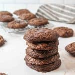 an upclose view of a stack of brownie mix cookies with more in the background