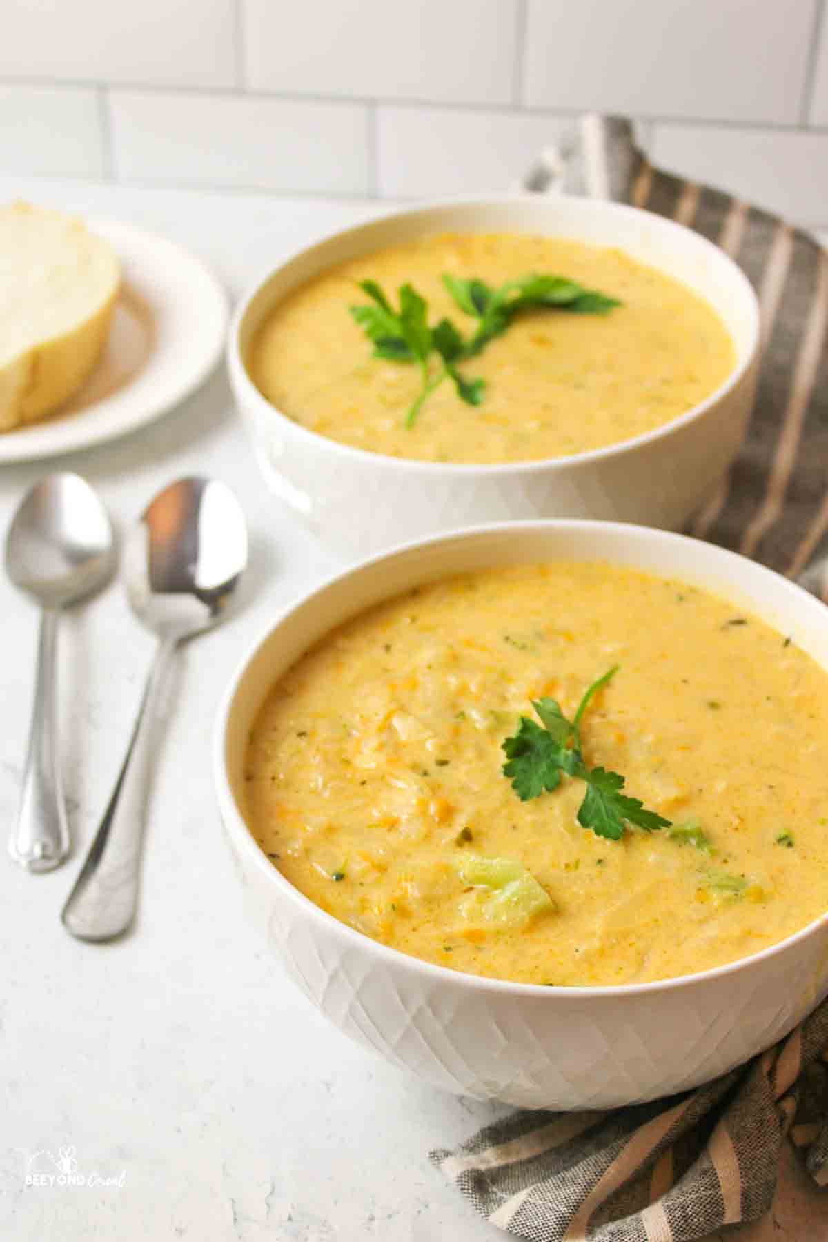 two bowls of potato soup next to two spoons