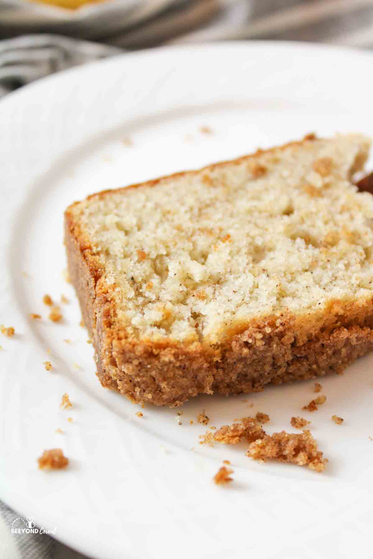 a slice of cinnamon crumble banana bread on a white plate.