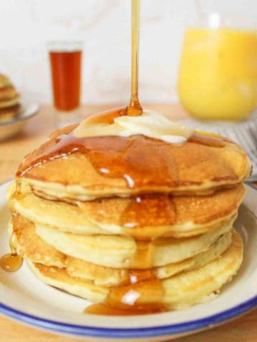 syrup drizzling over the top of butter topped pancakes.