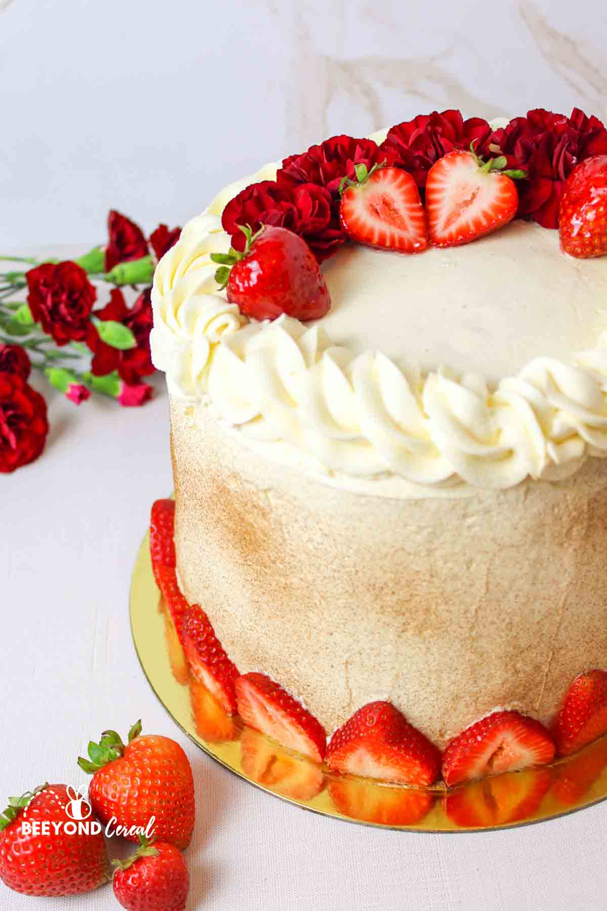 a strawberry and red flower garnishes tres leches cake.