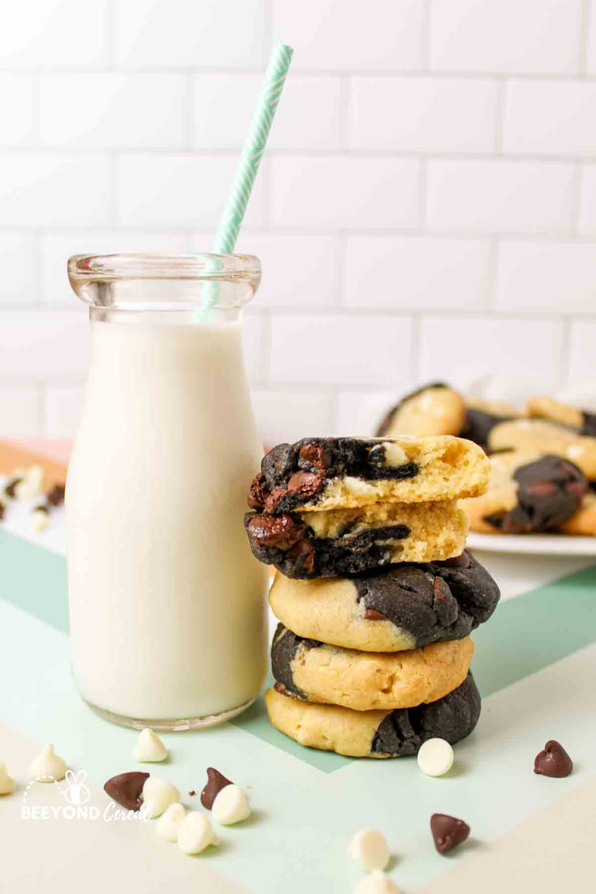 a bottle of milk next to a stack of cookies with the top one broken in half to reveal inside texture