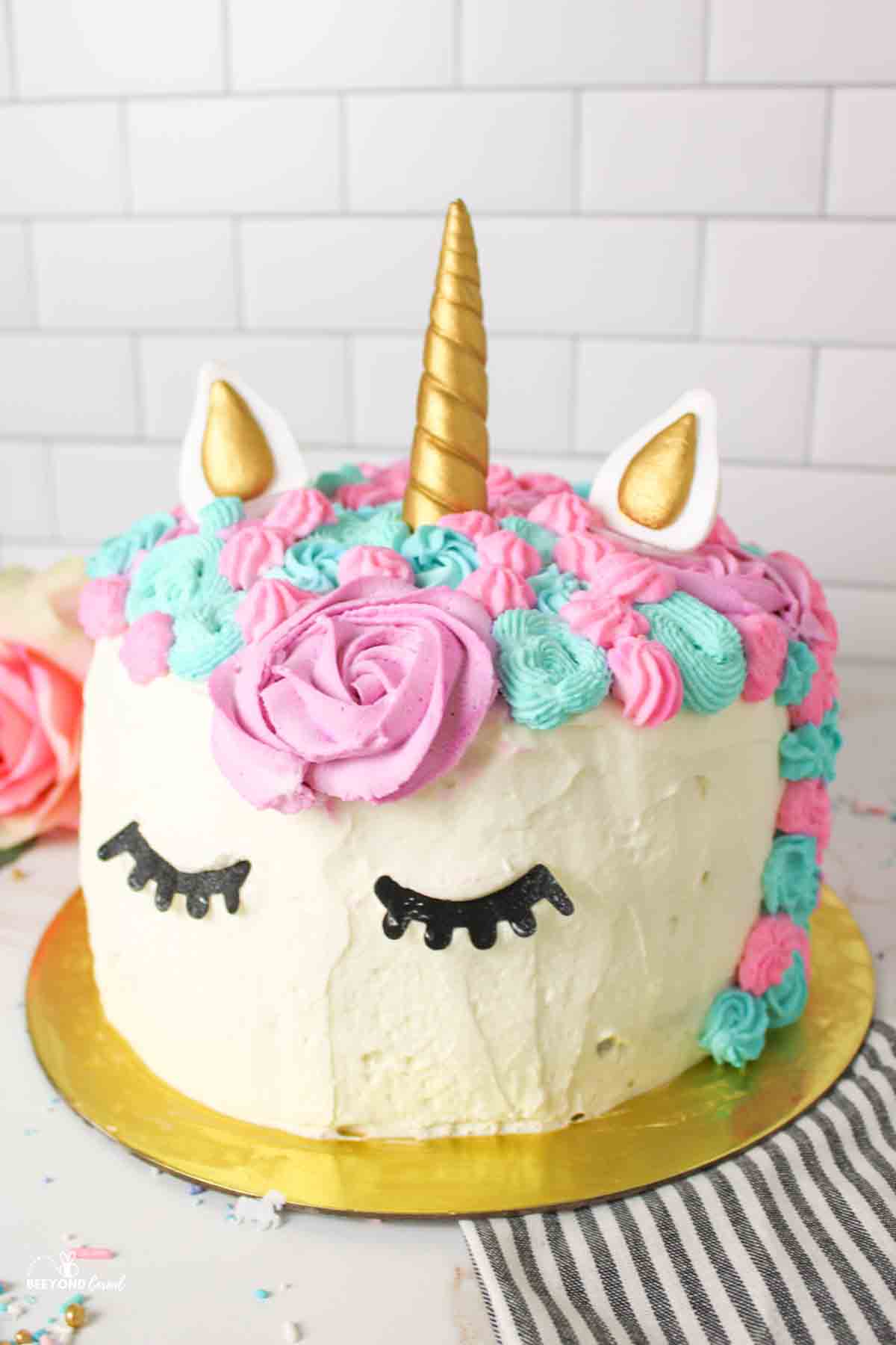 a finished unicorn cake with pink, purple, and blue hair.