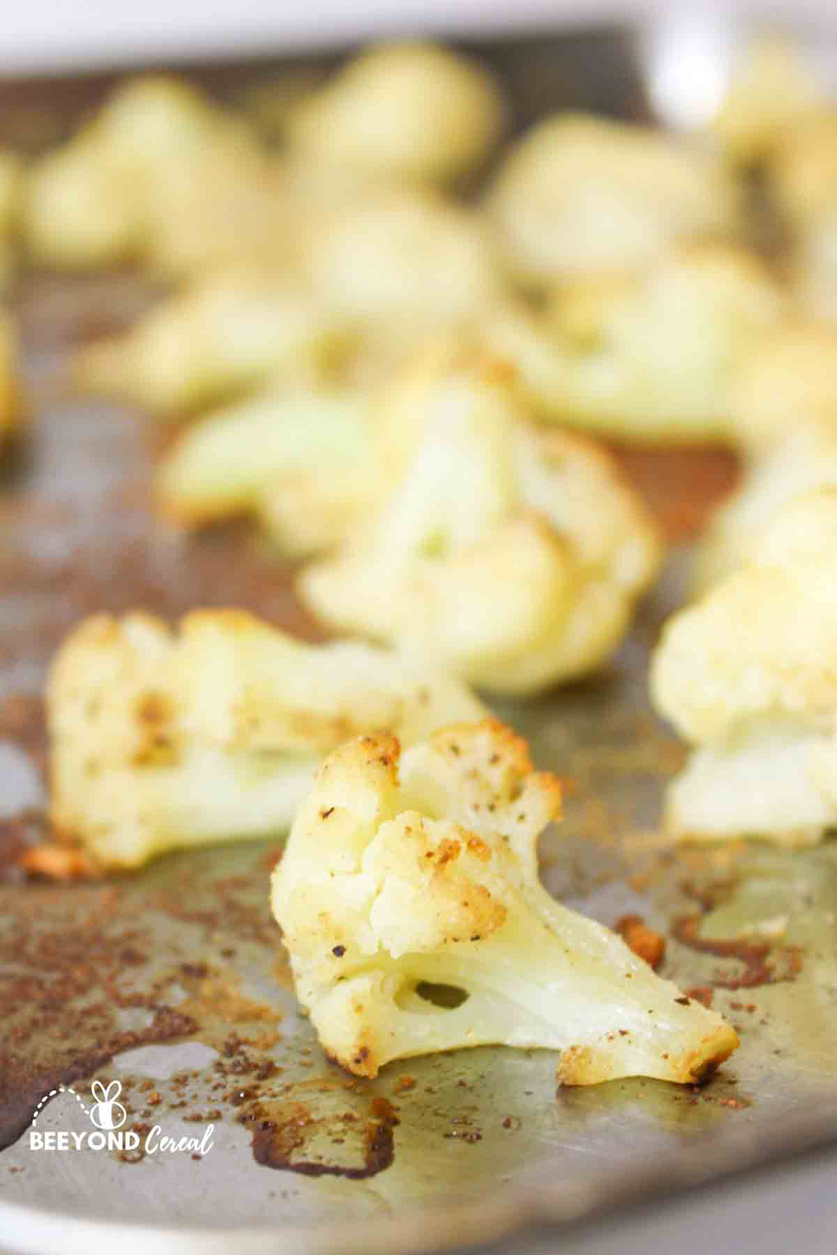 an upclose view of a roasted piece of cauliflower on a baking sheet