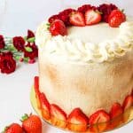 a close up of a layered tres leches cake with strawberries and red flowers