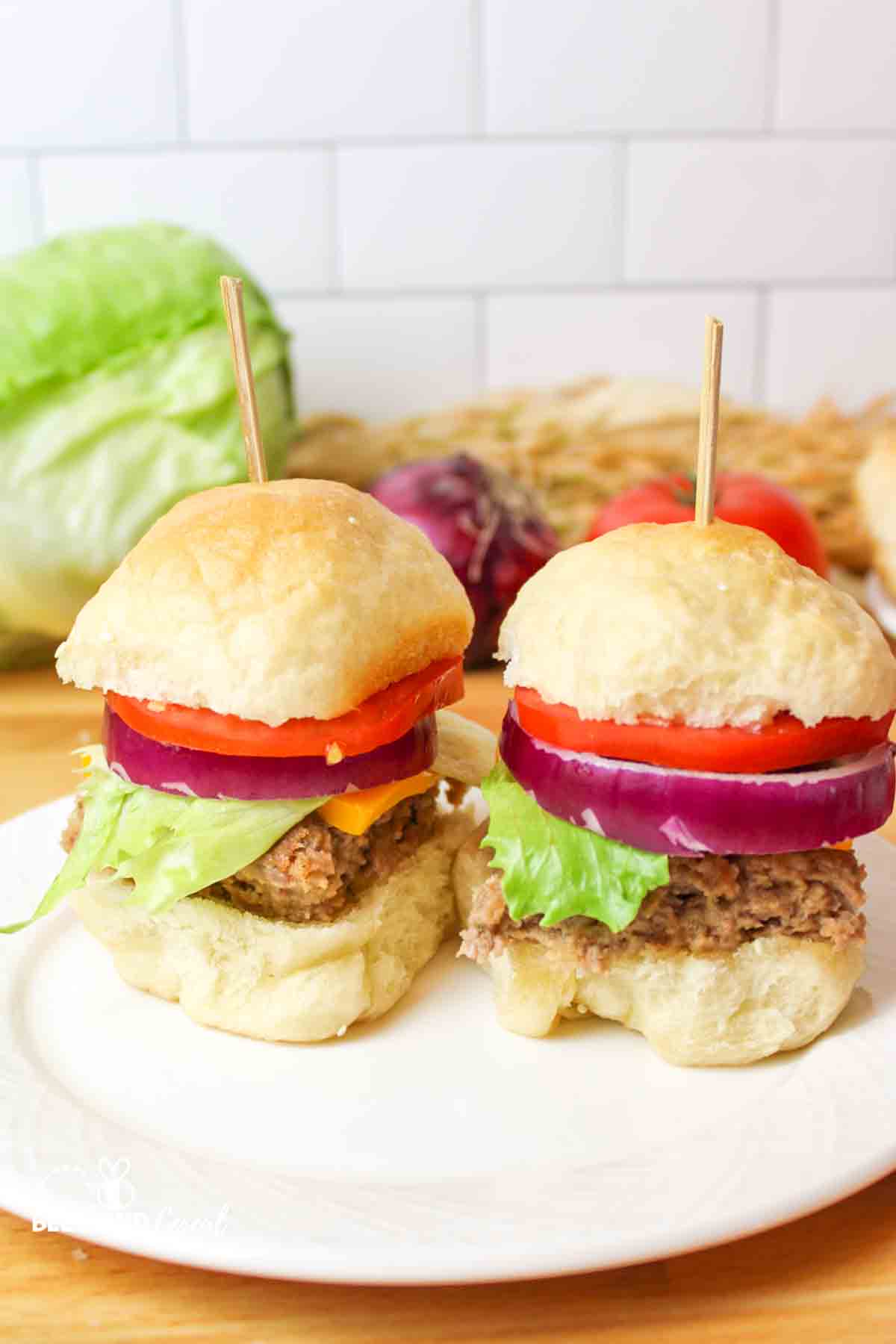 two hamburger sliders with homemade buns and toothpicks holding them together.