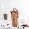 a tall glass of chocolate mocha iced coffee with scatterd coffee beans and chocolate bars