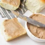 a close up view of cinnamon honey butter on bread rolls and in bowl with used knife