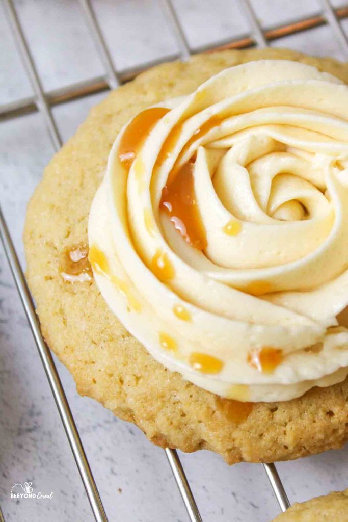 an upclose view of caramel sauce drizzled on top of a caramel buttercream topped apple cider cookie
