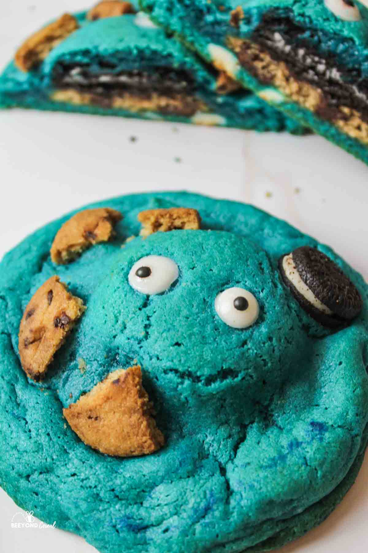 an upclose view of a blue cookie with candy eyes and cookie pieces on top
