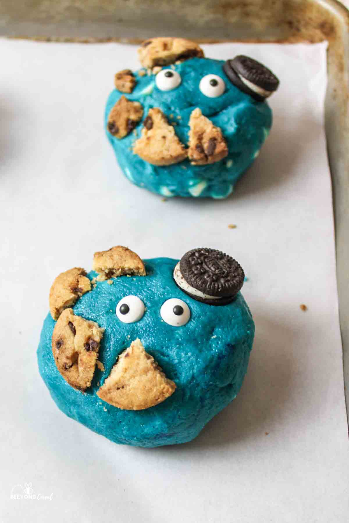 large blue cookie dough balls topped with candy eyes and broken cookie pieces.