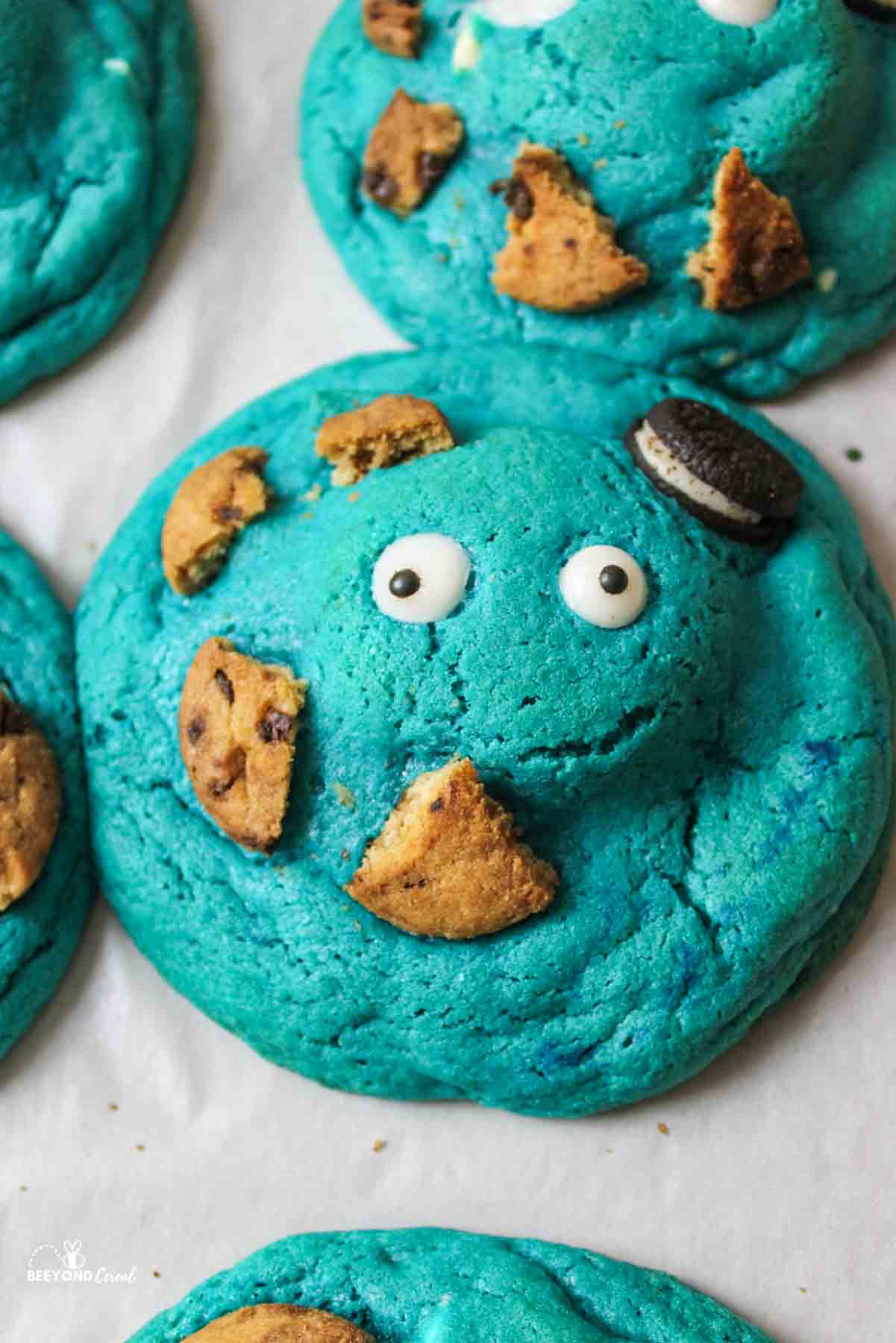 a close up of a blue cookie with candy eyes an broken smaller cookies on it