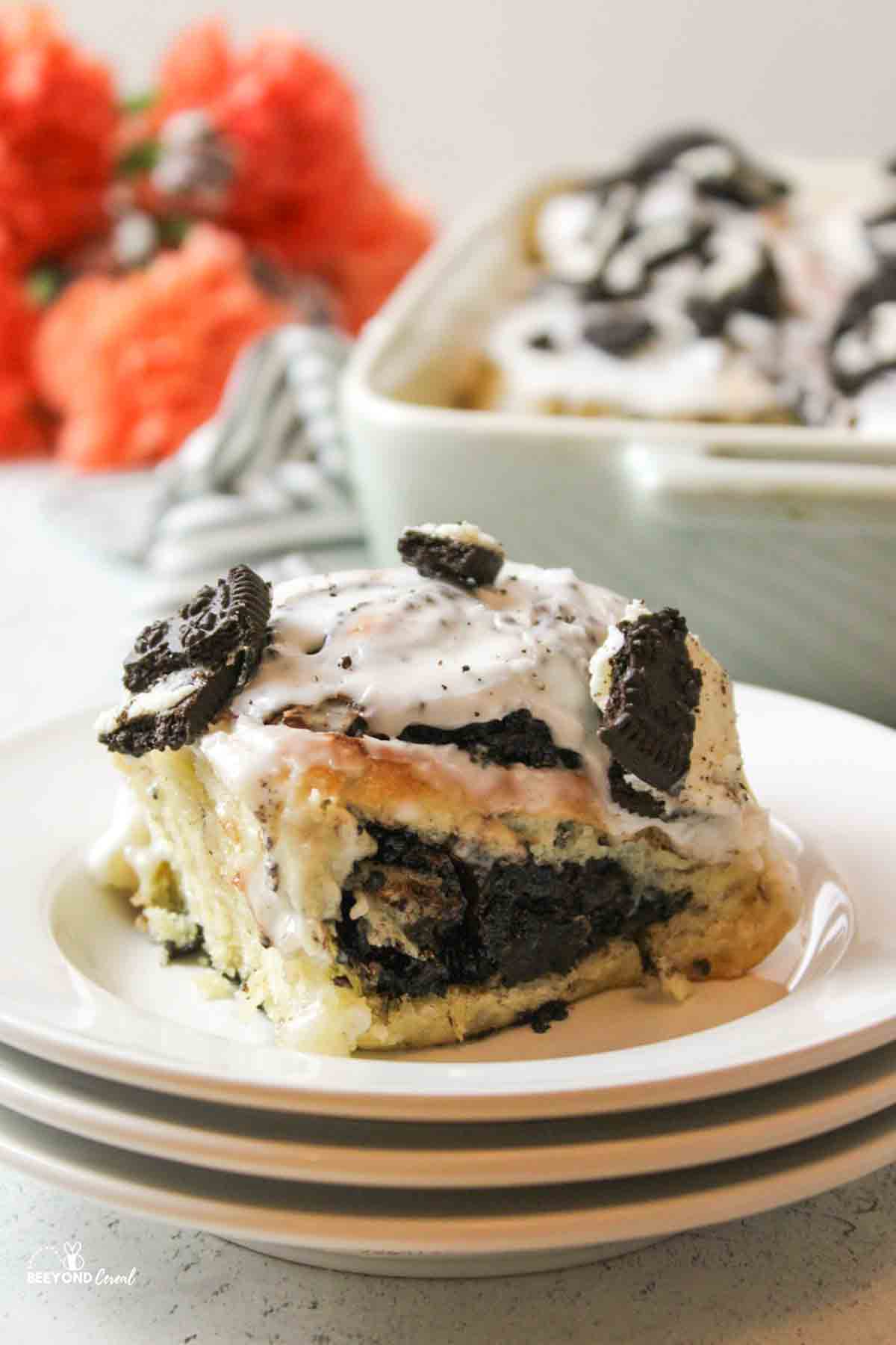 a stack of white plates topped with a cookies and cream oreo cinnamon roll.