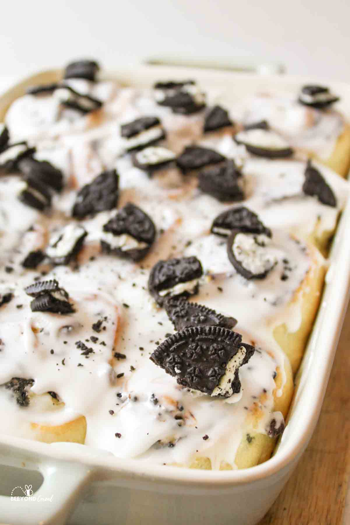 close up angled view of a baking dish full of oreo topped cinnamon rolls